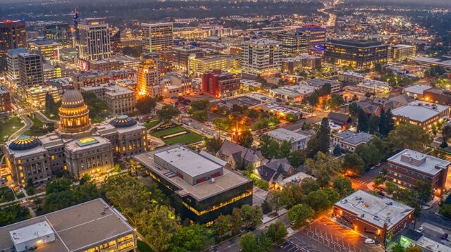 Aerial view of downtown Boise, Idaho at dusk, prominently featuring the illuminated State Capitol building and surrounding city skyline.
