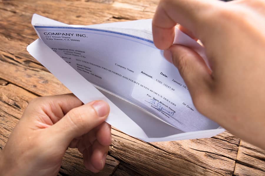 Opening an envelope that contains a paycheck.