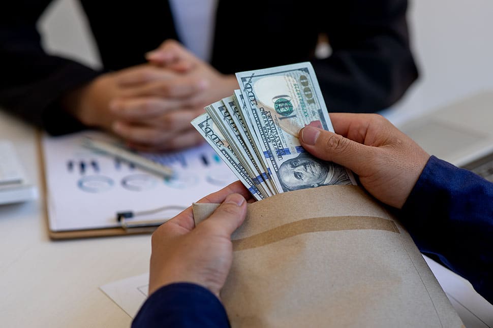 Tax Settlement Scams - Cash being taken out of the envelope as to bribe a person sitting in front.