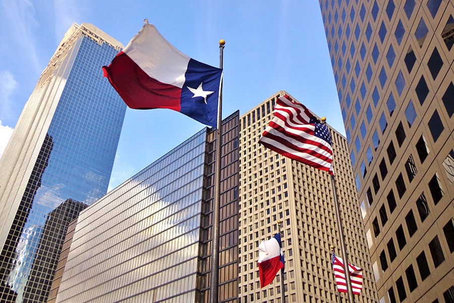 Texas and the US flag in front of business buildings.