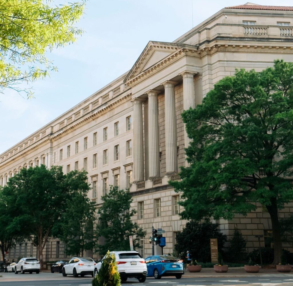 The Internal Revenue Service government building North Wing with grand architecture in Washington, DC, surrounded by cars and trees.