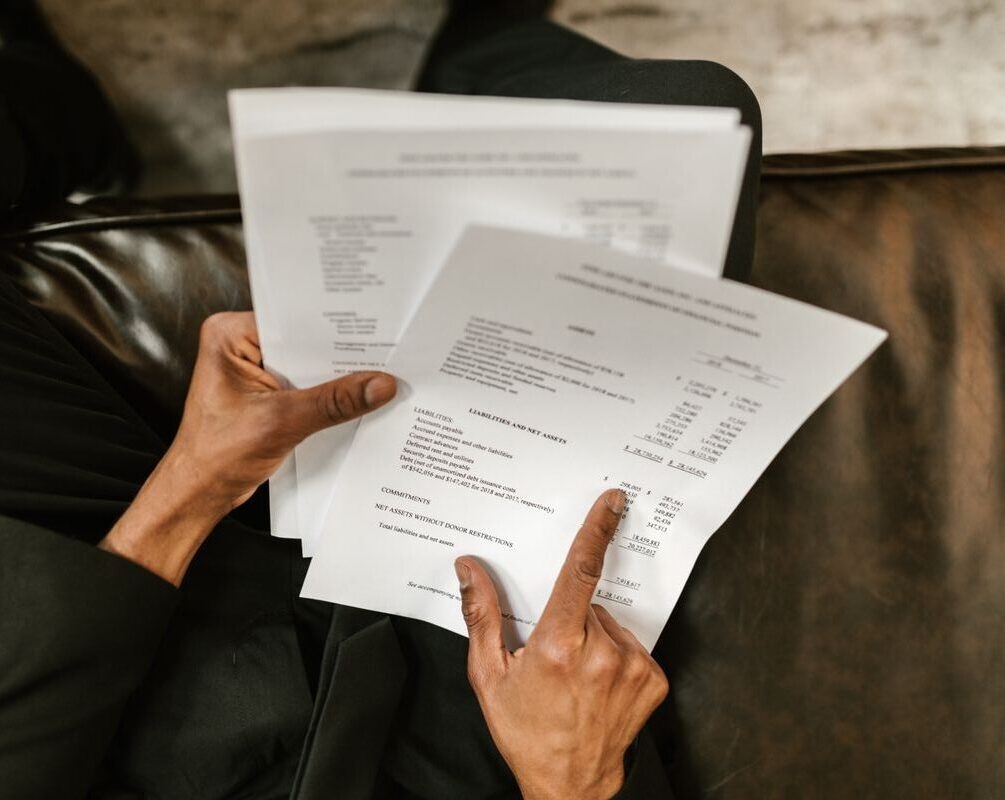 Close-up of a business professional reading and pointing at financial documents.